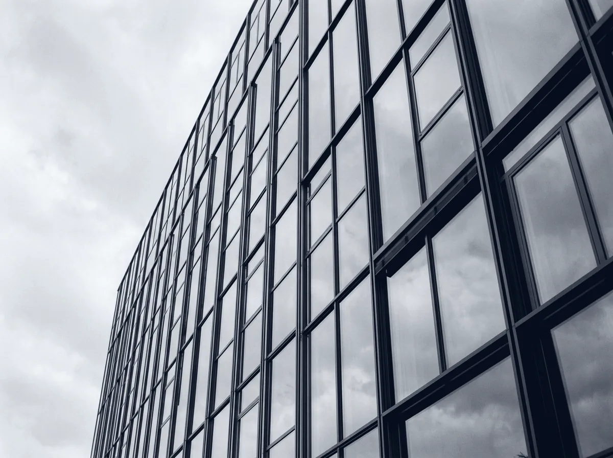 Glasfassade eines Hochhauses in Aufsicht mit klaren Fensterlinien
